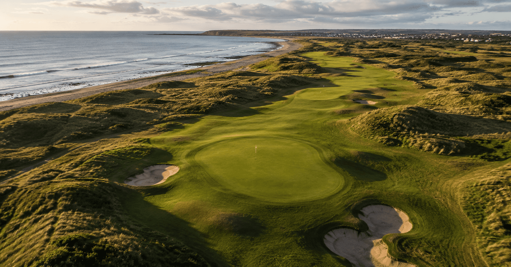 Aerial view of a links golf course with ocean backdrop, UK